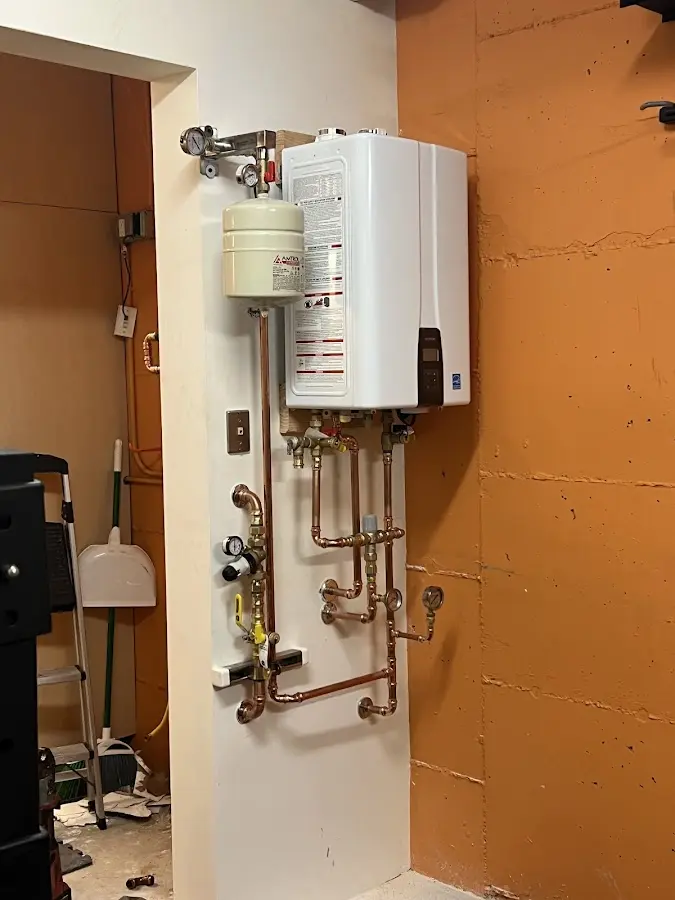 Plumbing technician inspecting water heater connections in University